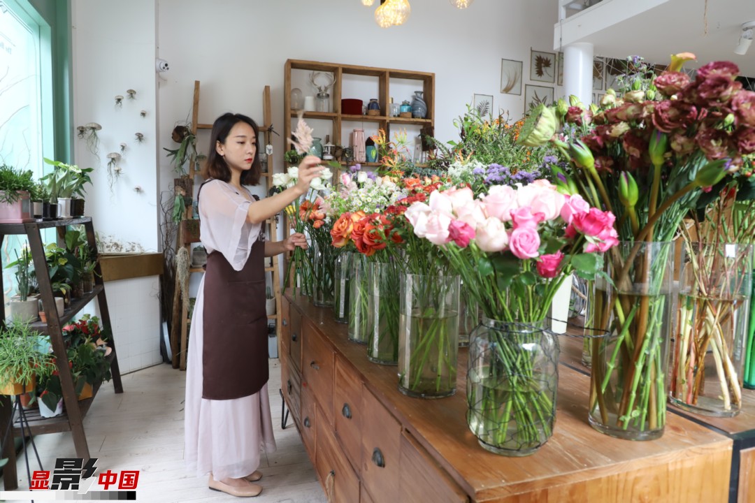 王黎媛是一名河南姑娘，在昆明念完大學后，就再也舍不下春城的藍天陽光、青山碧水，更舍不下這里的四時繁花，于是就干脆留了下來，成了一名媒體人。2017年的時候又毅然辭去工作，創(chuàng)業(yè)開起了花店，成了都市里的一名“花房姑娘”。圖為王黎媛在自己的花店中整理鮮花。新華網(wǎng) 周亞平/攝 念新洪/文